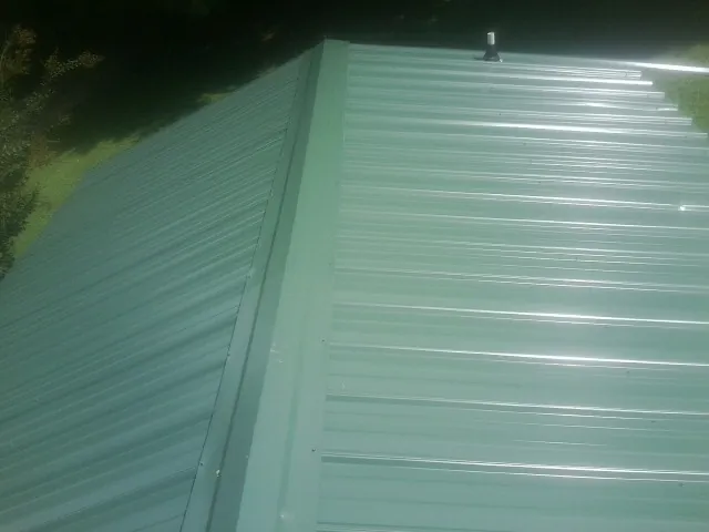New green metal panels meeting at the ridge of a roof — Flat Roof Repair work by our crew in Ripley
