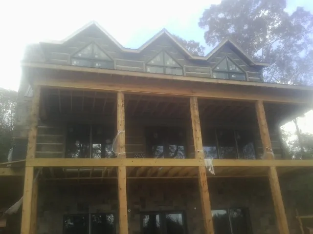 Dormers and porch framing on a large log home under construction — Roof Coating work by our crew in Ripley